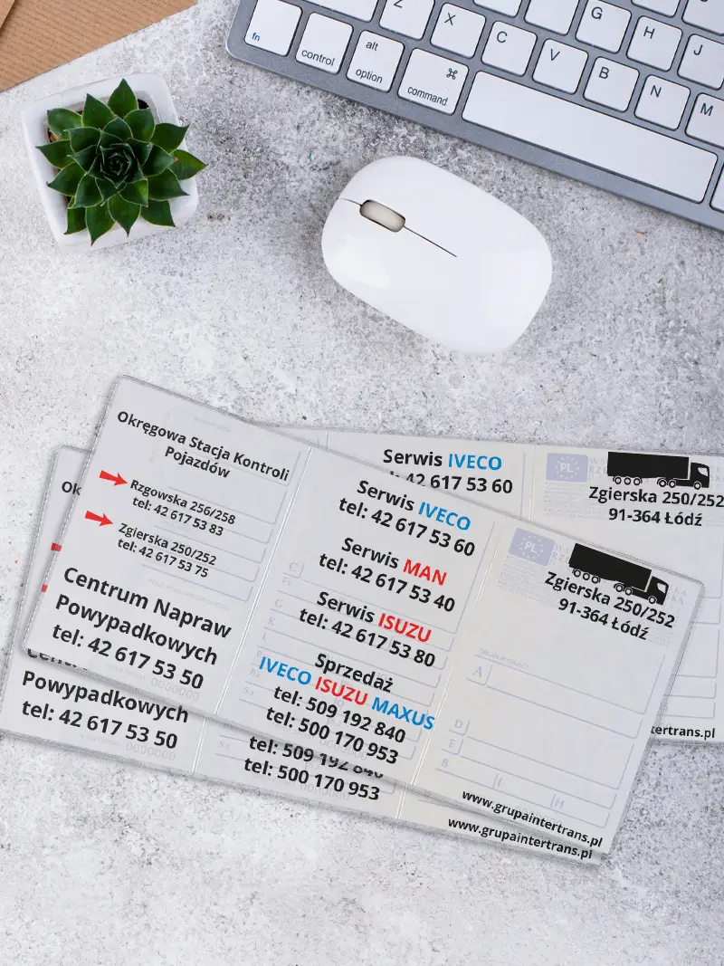 Zbliżenie na okładkę na dowód rejestracyjny prezentującą podział na serwisy IVECO, MAN i ISUZU, ułożoną na jasnym biurku obok białej myszki.