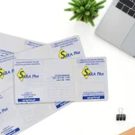 Rozłożone okładki na dowody rejestracyjne z dwukolorowym logo SARA Plus ułożone na białym blacie biurka w pobliżu laptopa i rośliny.