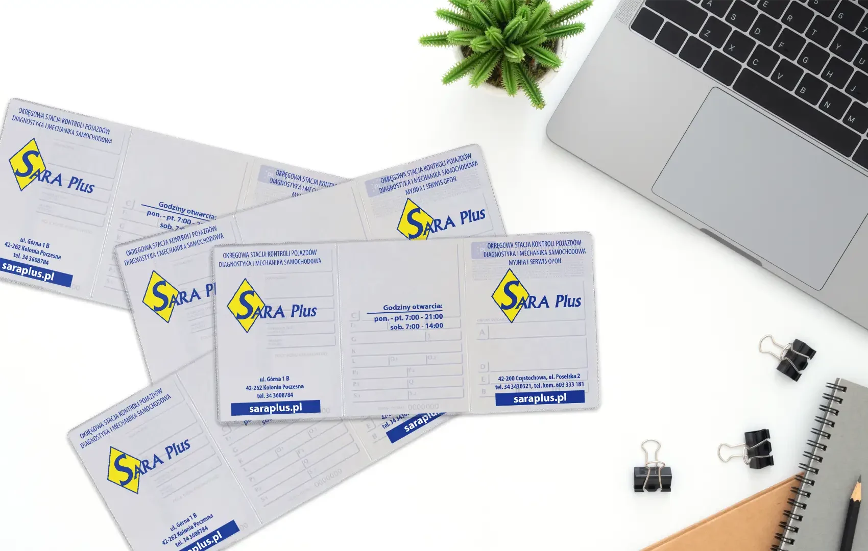 Rozłożone okładki na dowody rejestracyjne z dwukolorowym logo SARA Plus ułożone na białym blacie biurka w pobliżu laptopa i rośliny.