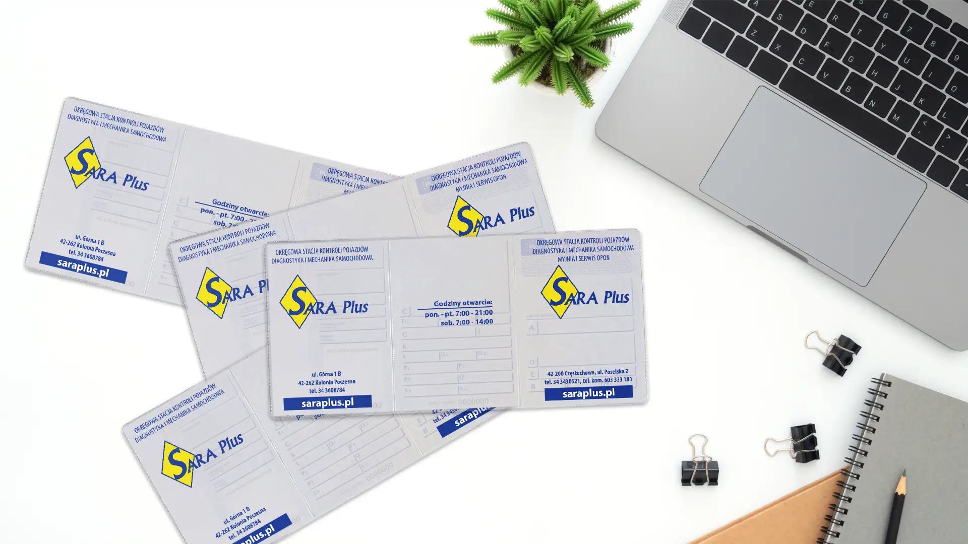 Rozłożone okładki na dowody rejestracyjne z dwukolorowym logo SARA Plus ułożone na białym blacie biurka w pobliżu laptopa i rośliny.
