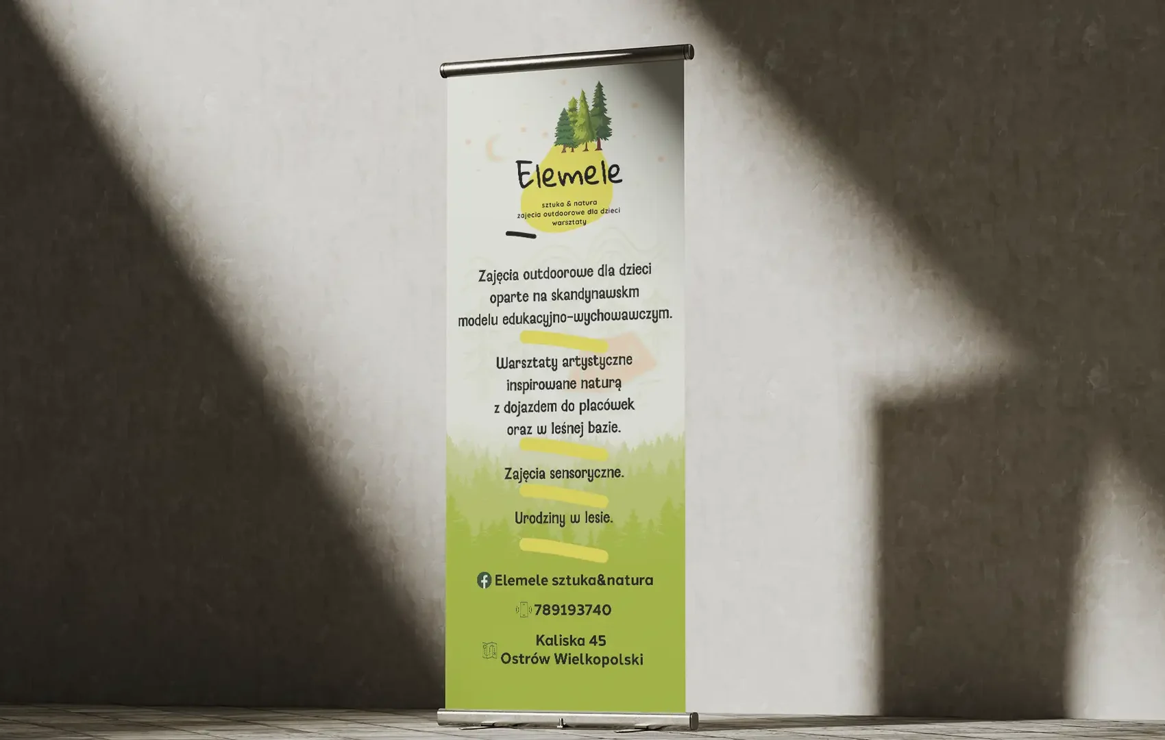 Roll-up reklamowy Elemele z motywem lasu, ustawiony na teksturowanej ścianie w Ostrowie Wielkopolskim.