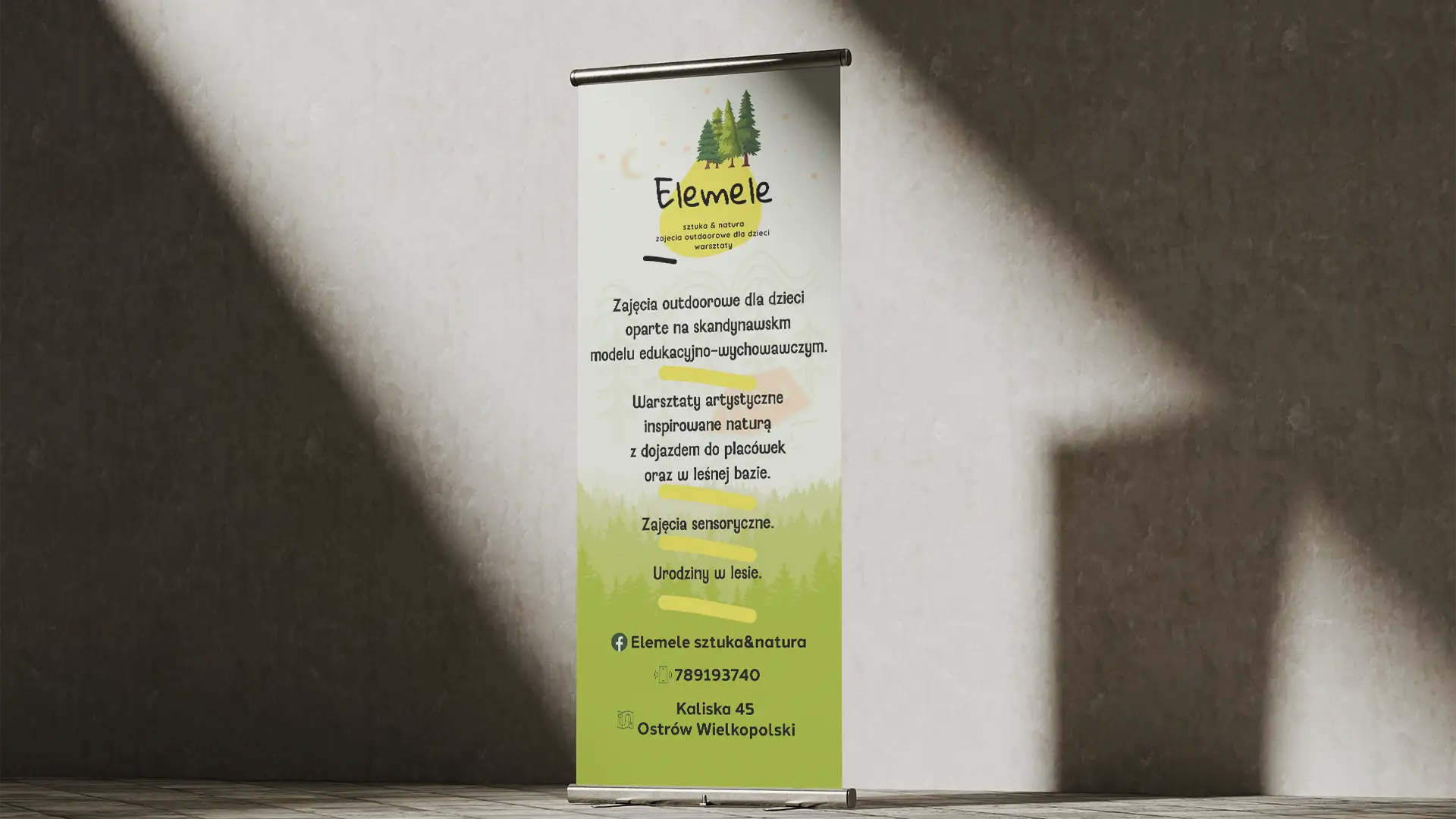 Roll-up reklamowy Elemele z motywem lasu, ustawiony na teksturowanej ścianie w Ostrowie Wielkopolskim.
